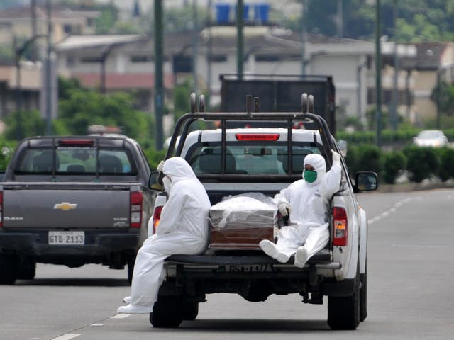 People wearing protective suits accompany a coffin on a truck near Los Ceibos hospital in Guayaquil