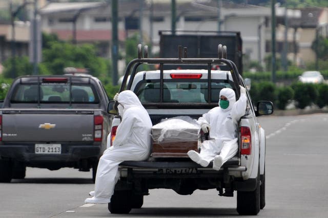 People wearing protective suits accompany a coffin on a truck near Los Ceibos hospital in Guayaquil