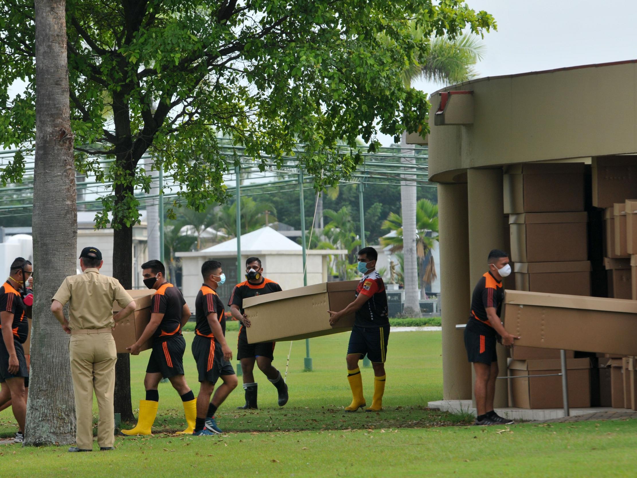 Soldiers transport cardboard boxes used as coffins at the Paque de la Paz cemetery in Guayaquil