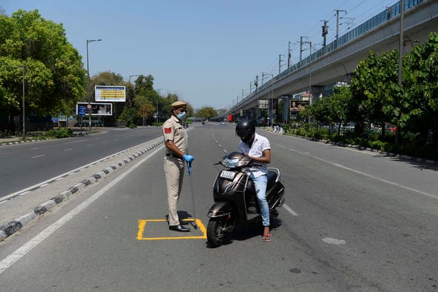 File: A police officer stops a motorist at a checkpoint on a deserted road in Delhi