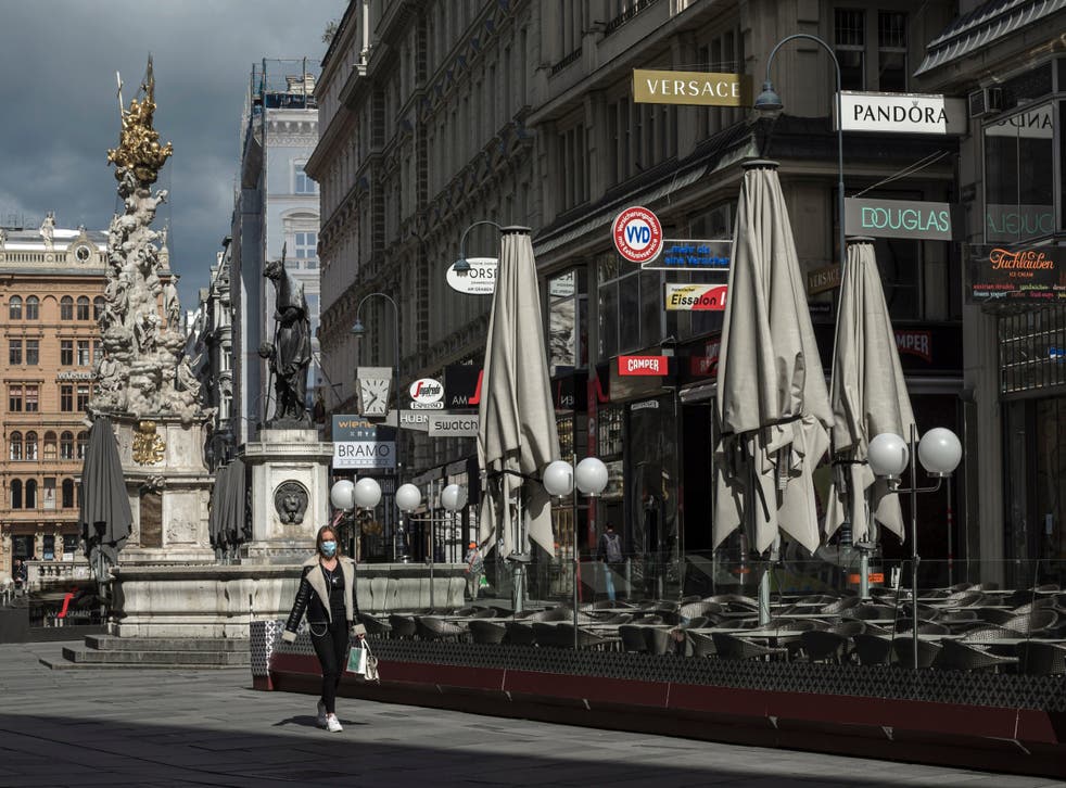 A woman wearing a face mask walks through downtown Vienna, Austria