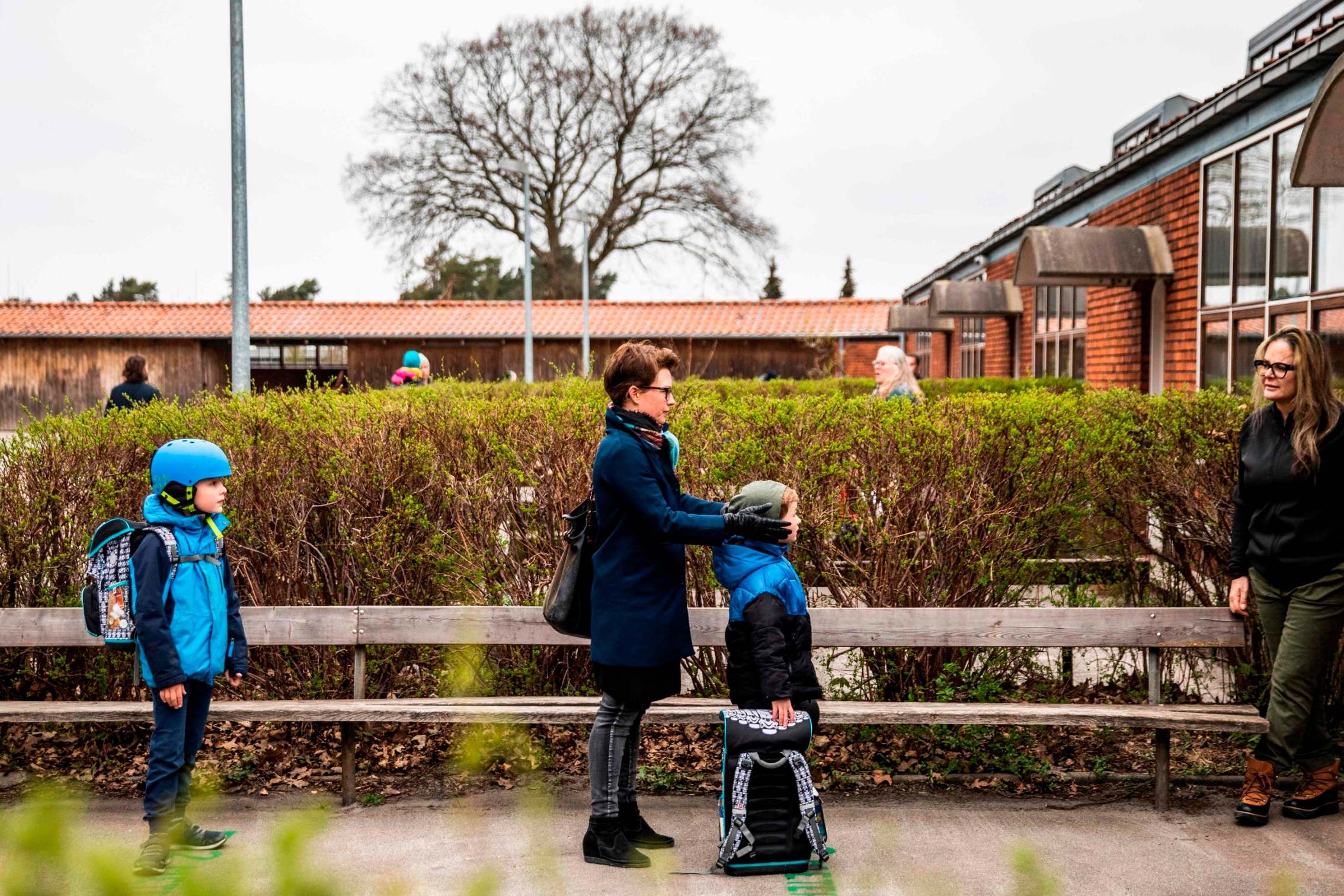Parents with their children stand in queue waiting to get inside Stengaard School north of Copenhagen, Denmark