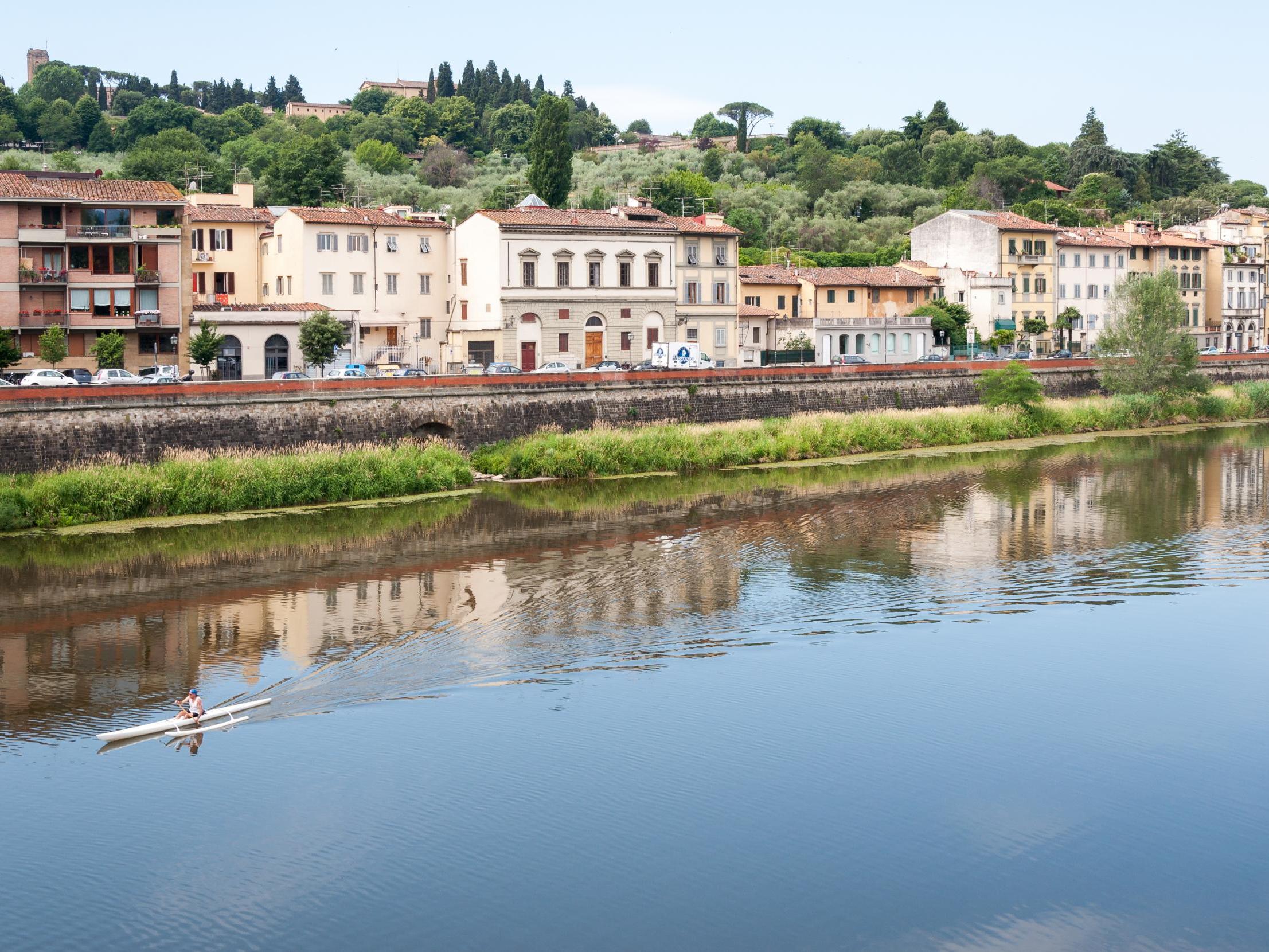 A man rowing a canoe on the Arno river in Florence, Italy
