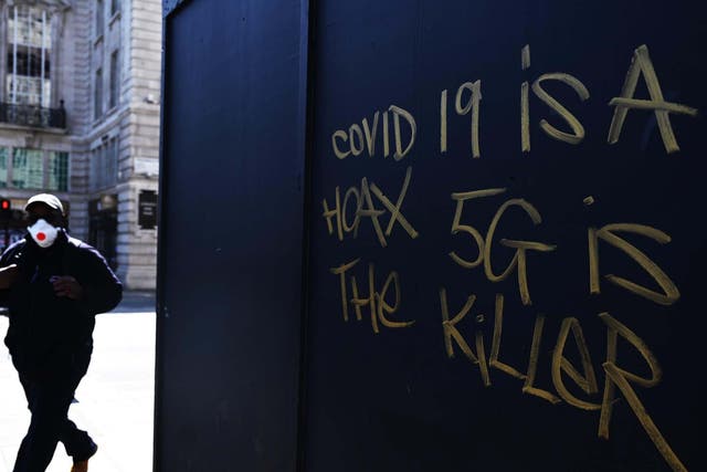 A man in a mask passes 5G conspiracy graffiti in London this week