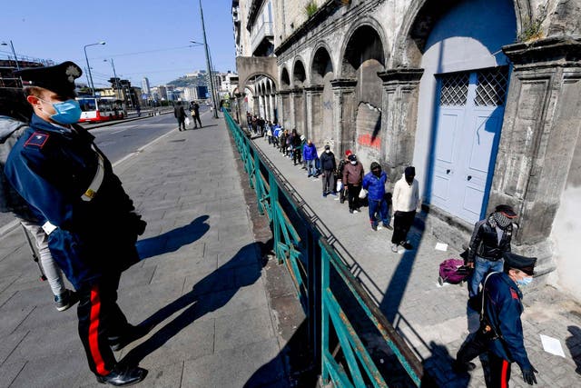 People line up outside a soup kitchen in Naples amid the coronavirus crisis