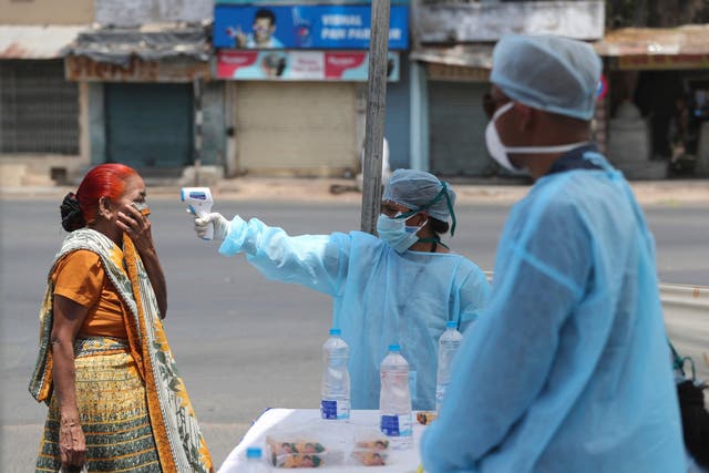 An Indian health worker checks the temperature of a woman during lockdown in Ahmedabad, Gujarat