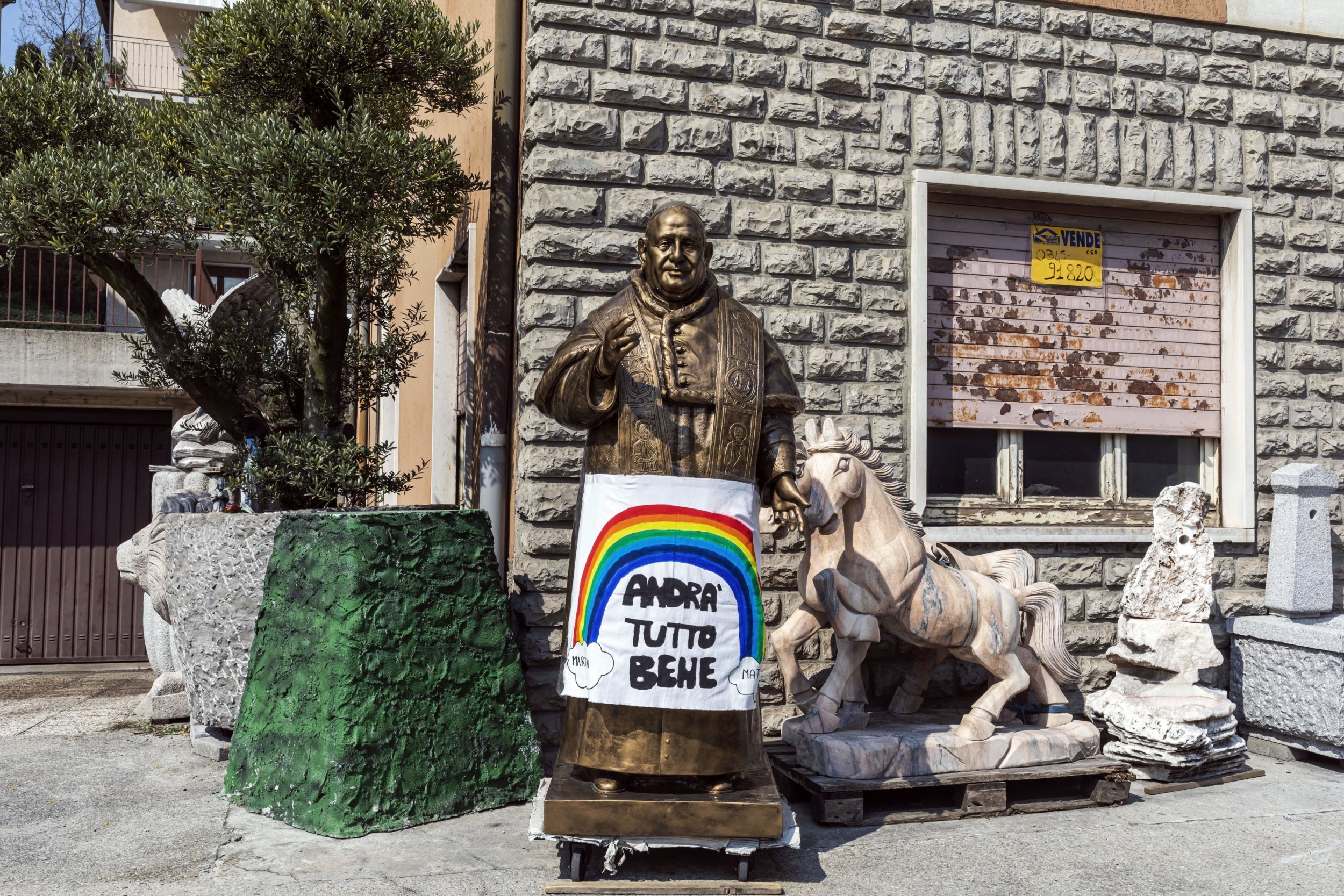 A statue of the late Pope John XXIII, originally from the province of Bergamo, is seen with a sign that reads ‘everything will be fine’ (Getty)