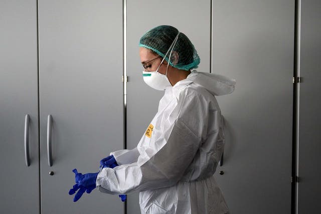 A nurse puts on protective equipment in a new hospital near Alba