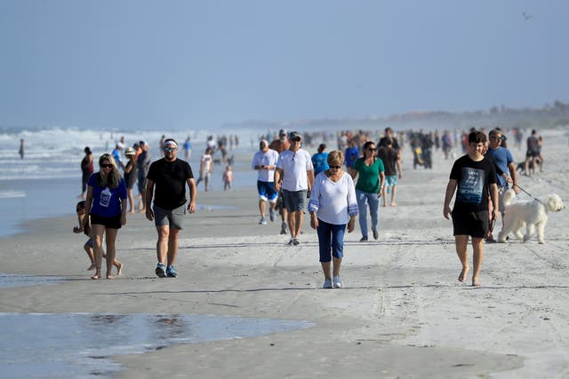 People are seen at the beach on April 17, 2020 in Jacksonville Beach, Florida. Jacksonville Mayor Lenny Curry announced Thursday that Duval County's beaches would open at 5 p.m. but only for restricted hours and can only be used for swimming, running, surfing, walking, biking, fishing, and taking care of pets.