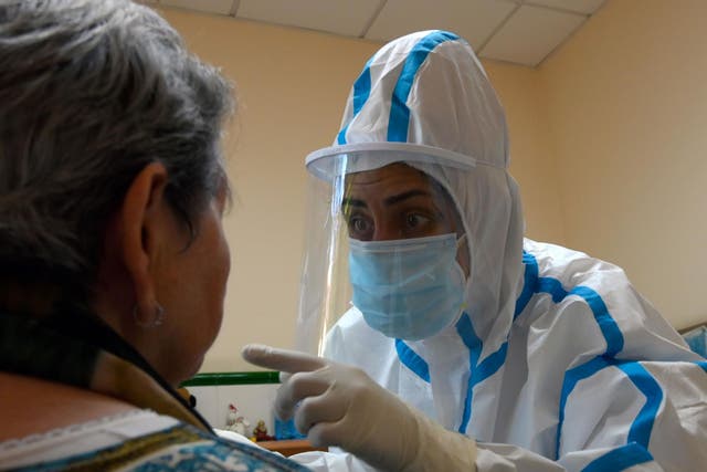 A healthcare worker wearing a protective suit takes a swab sample from a care home resident