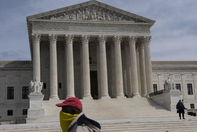 A man wearing a makeshift mask walks in front of the US Supreme Court on 24 March 24 2020