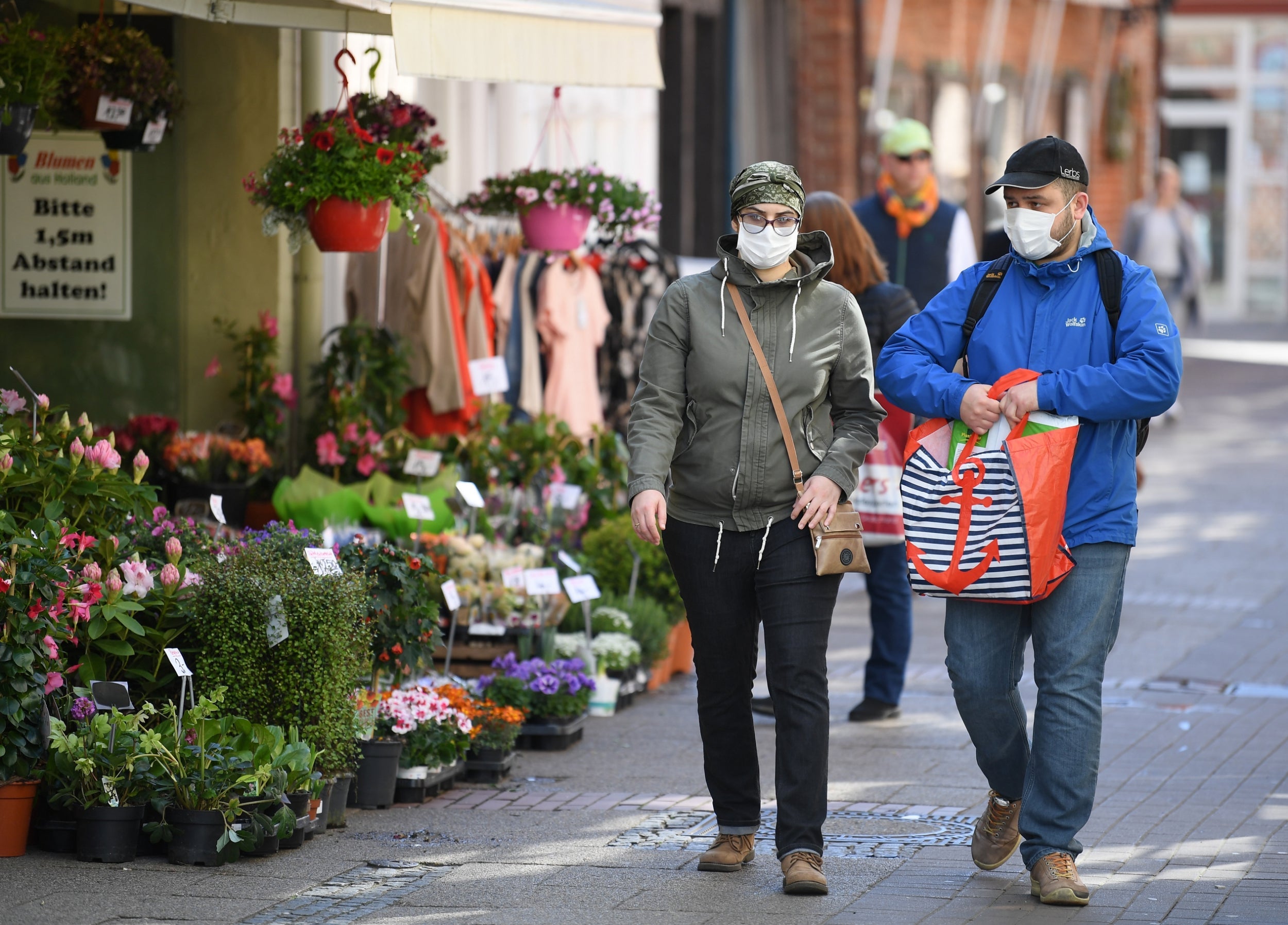 A couple walk past a florist on the first day of the easing of some restrictions in Lueneburg, Germany