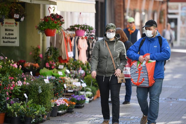 A couple walk past a florist on the first day of the easing of some restrictions in Lueneburg, Germany