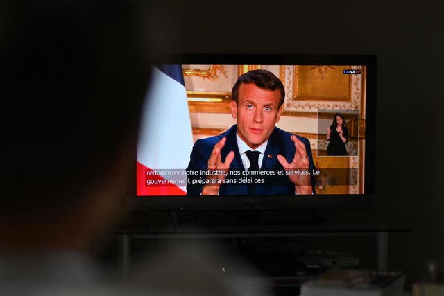 A spectator watches TV in Paris, as French President Emmanuel Macron speaks from the Elysee Palace during a televised address to the nation on 13 April