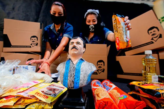 Employees of the Alejandrina Guzman Foundation, one wearing a face mask with the image of Mexican drug lord Joaquin "El Chapo" Guzman - Alejandrina's father -, arrange boxes with basic goods to be donated to people in need