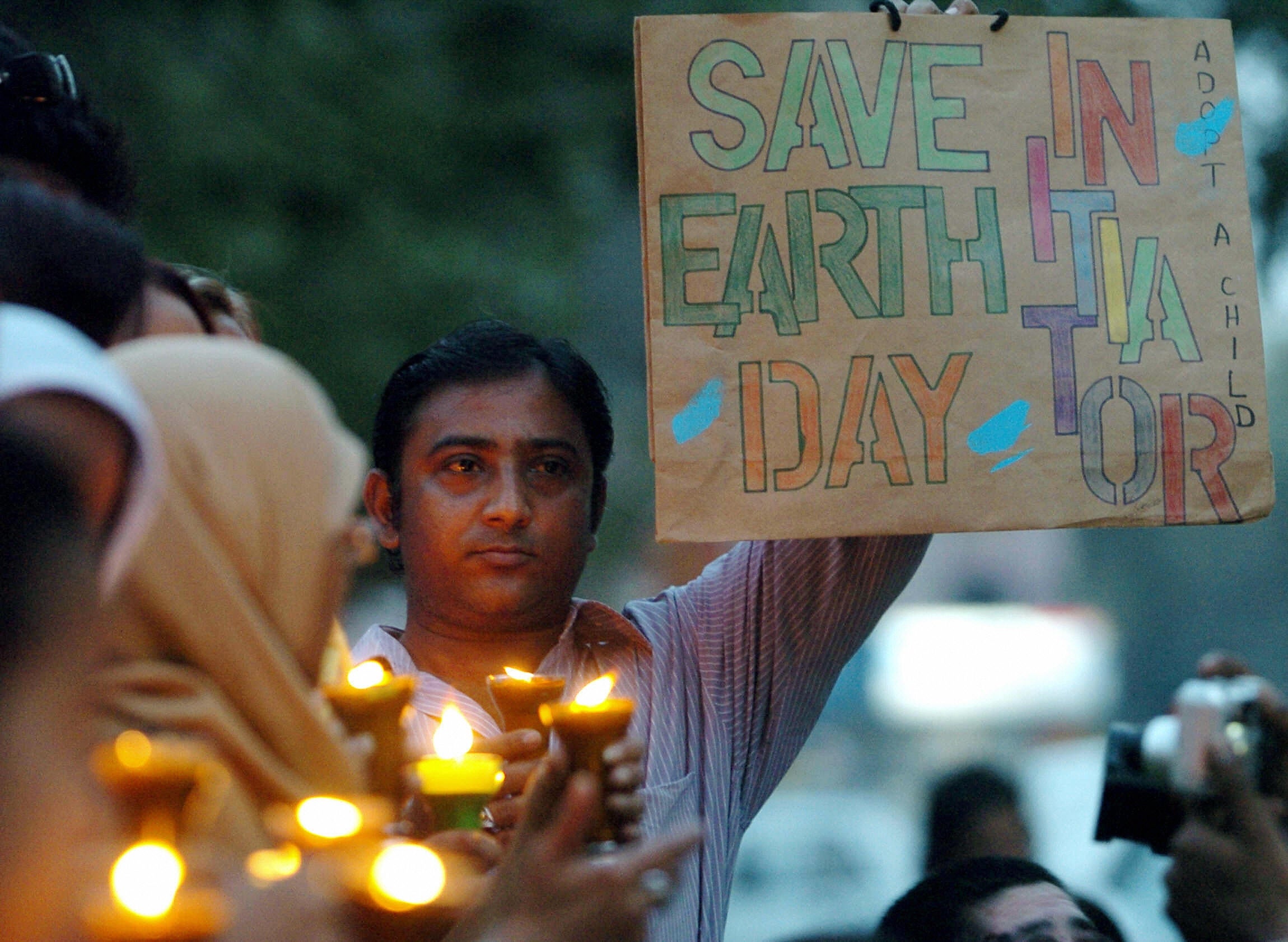 A Pakistani activist displays a placard as others hold candles during a demonstration to mark International Earth Day in Karachi, 21 April, 2005. (AAMIR QURESHI/AFP via Getty Images)