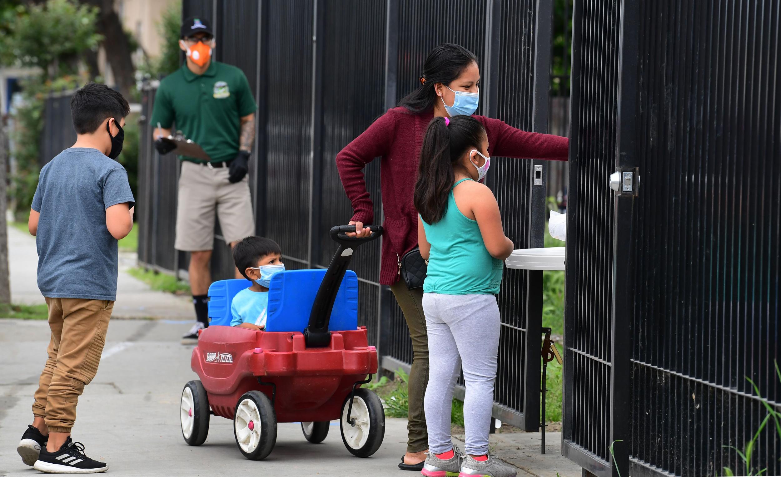 The number of infected children is significantly lower than adults but families, like this one in California seen collecting food from a temporary food bank, remain at risk of catching the virus