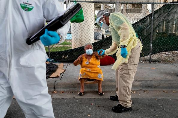 A worker of Miami-Dade County Homeless Trust helps a homeless woman, after testing her for coronavirus disease (COVID-19) in Downtown Miami. The US is facing hunger and homeless crises that have been exacerbated by the pandemic.
