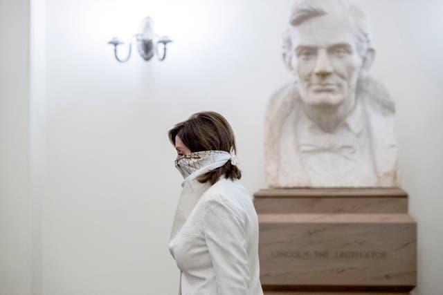 House Speaker Nancy Pelosi, wearing a face covering, walks past a bust of President Abraham Lincoln as she arrives on Capitol Hill for a debate on a bailout during the coronavirus pandemic. (Photo by AP)