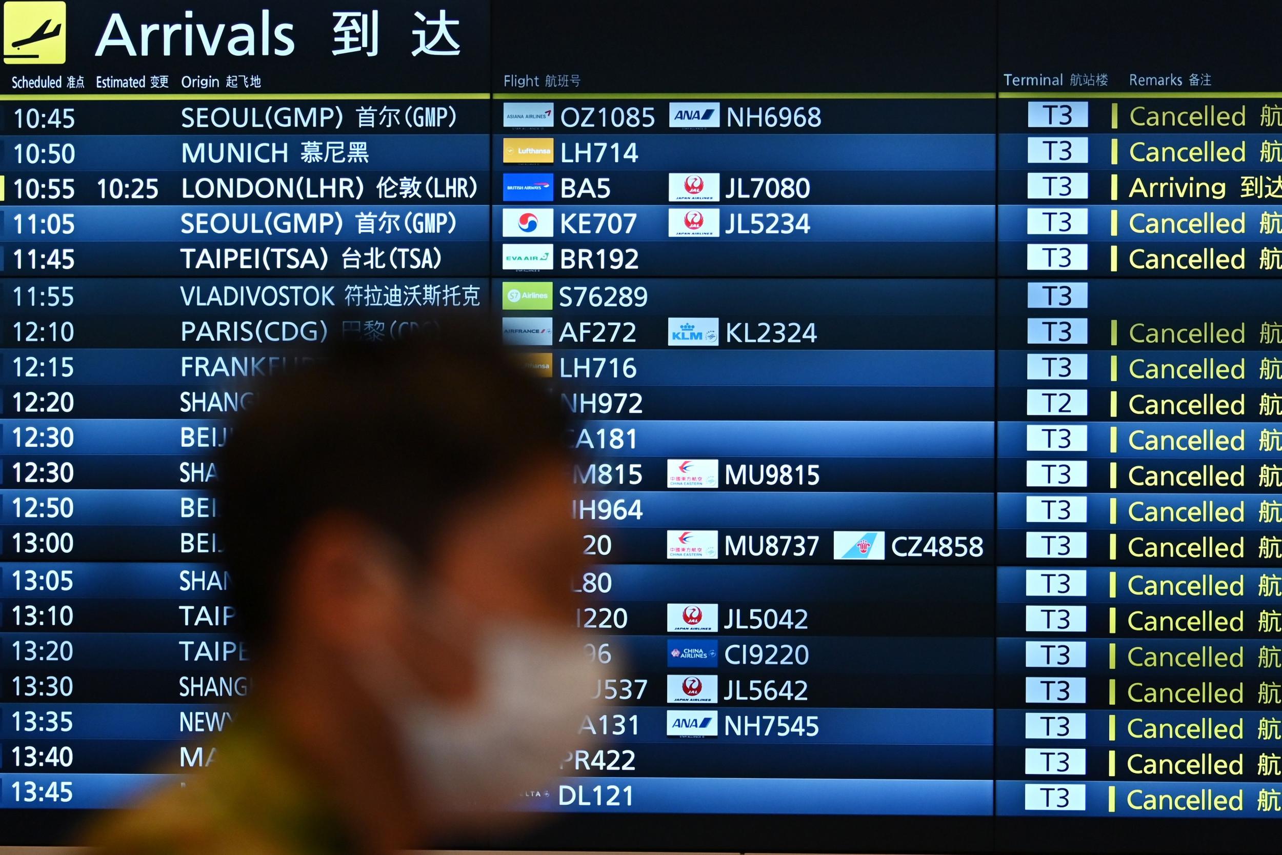 A man walks past a signboard displaying cancelled flights at an arrivals floor of the international terminal at Haneda airport in Tokyo
