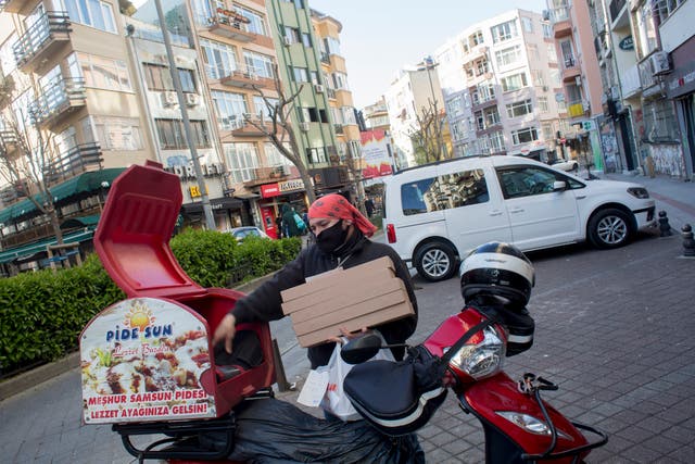 Ferit Buyuk stacks a pile of pizza boxes into the insulated box onto the back of his motor scooter in Istanbul.