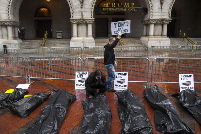 Melissa Byrne, with a group calling themselves The People's Motorcade, prays in front of replicas of body bags placed on the sidewalk in front of the Trump International Hotel in Washington