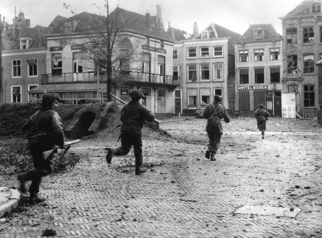 Allied assault troops dash through the streets of the liberated town of Flushing in the Netherlands to clear our remaining enemy snipers