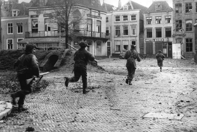 Allied assault troops dash through the streets of the liberated town of Flushing in the Netherlands to clear our remaining enemy snipers