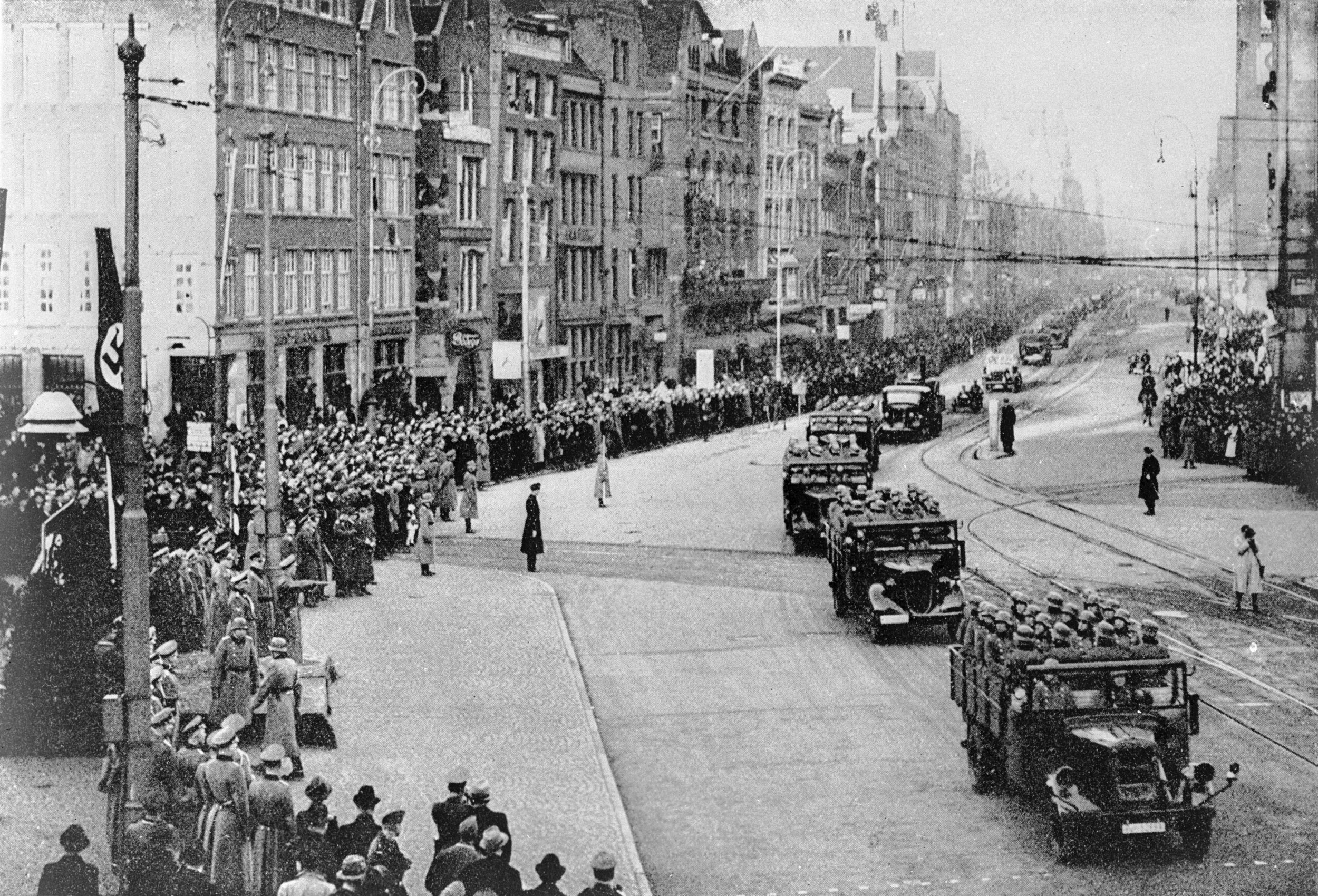 Nazi troops and armoured divisions drive along a main street in Amsterdam