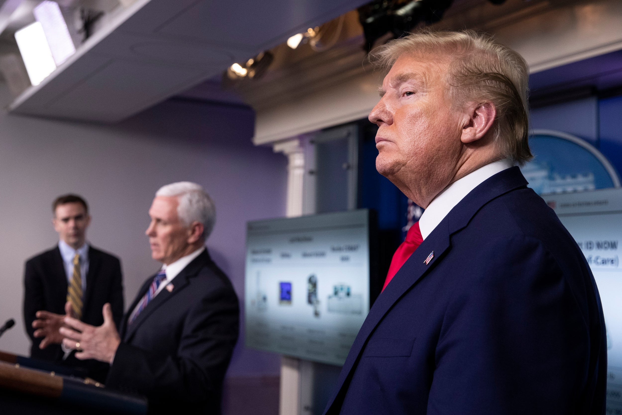 Donald Trump looks on as Mike Pence speaks during a White House briefing on the coronavirus pandemic