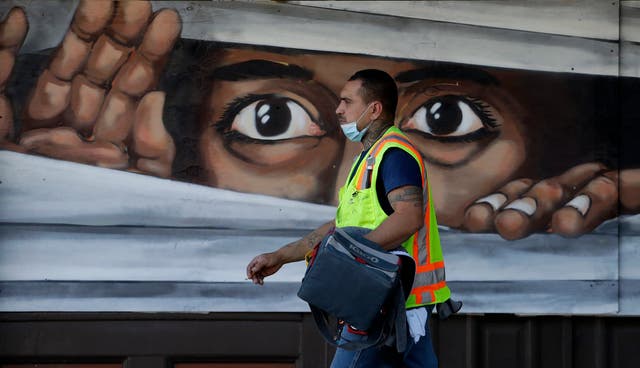 A construction worker walks past a mural painted on a wall in Austin, Texas during the coronavirus pandemic