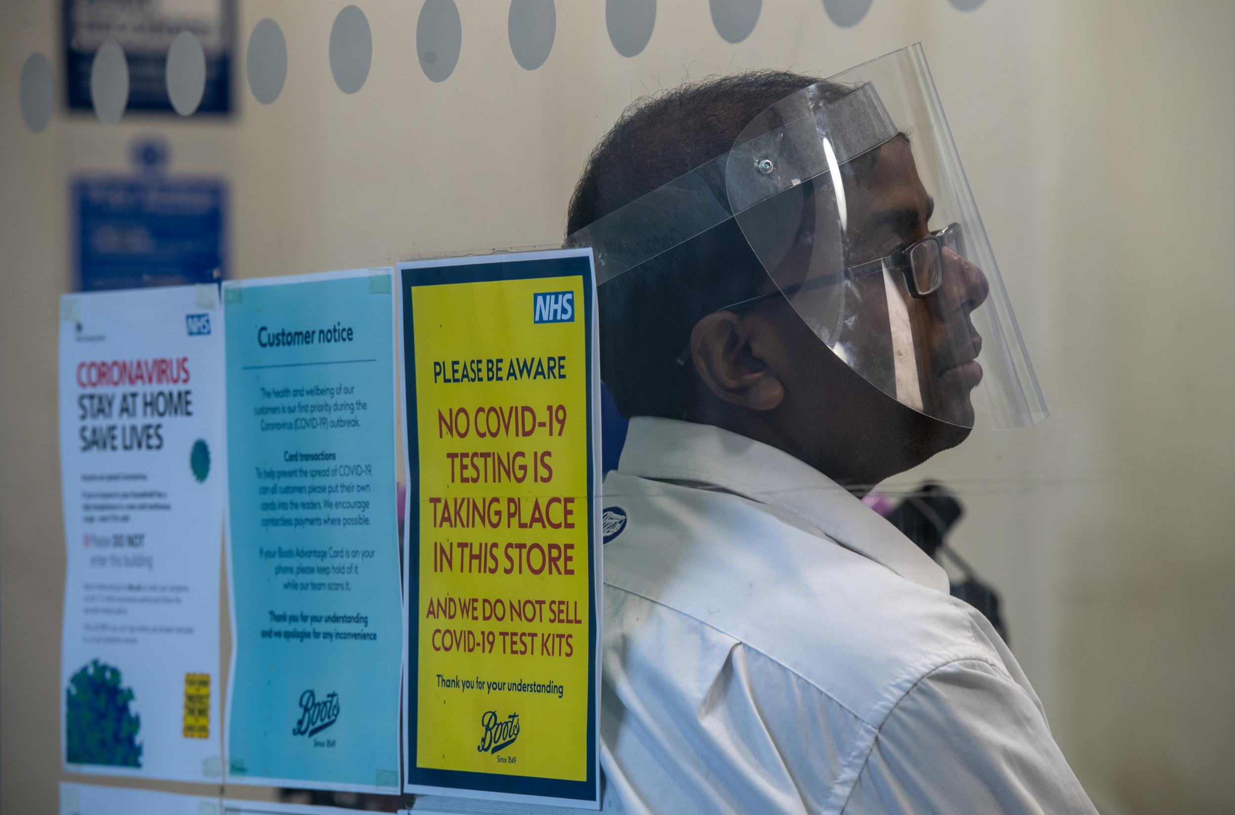 A Boots pharmacy employee wears a face shield whilst working