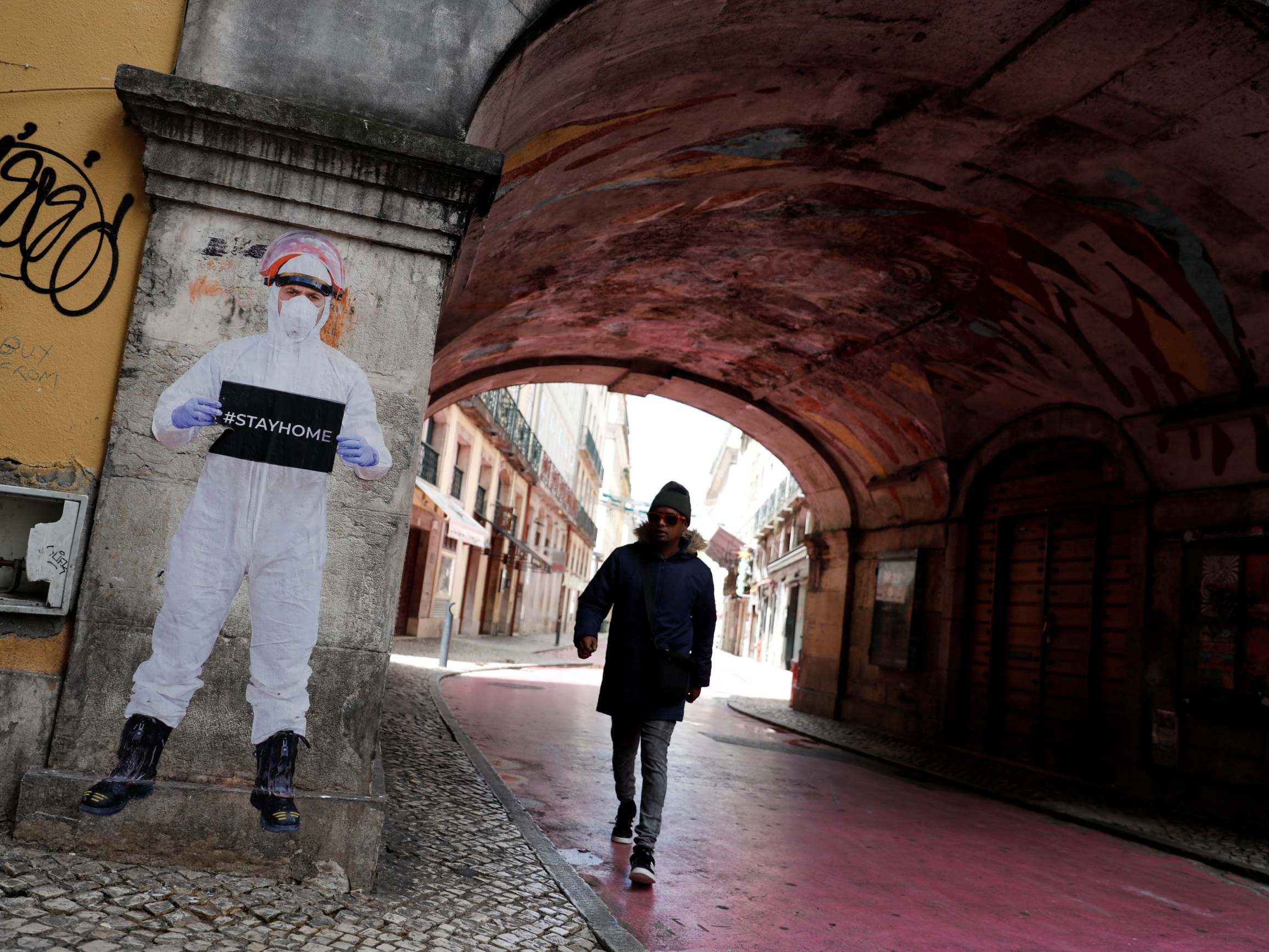 A man walks next to a picture of photographer Salvador Colaco in downtown Lisbon