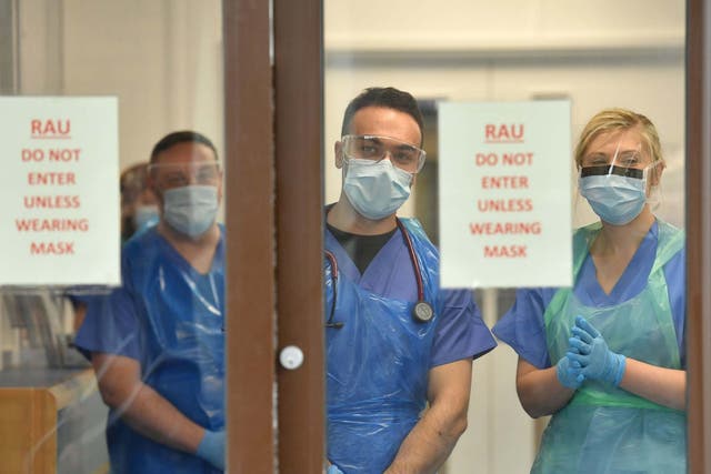 Medical staff in the UK wearing personal protective equipment (PPE) wait to receive coronavirus patients