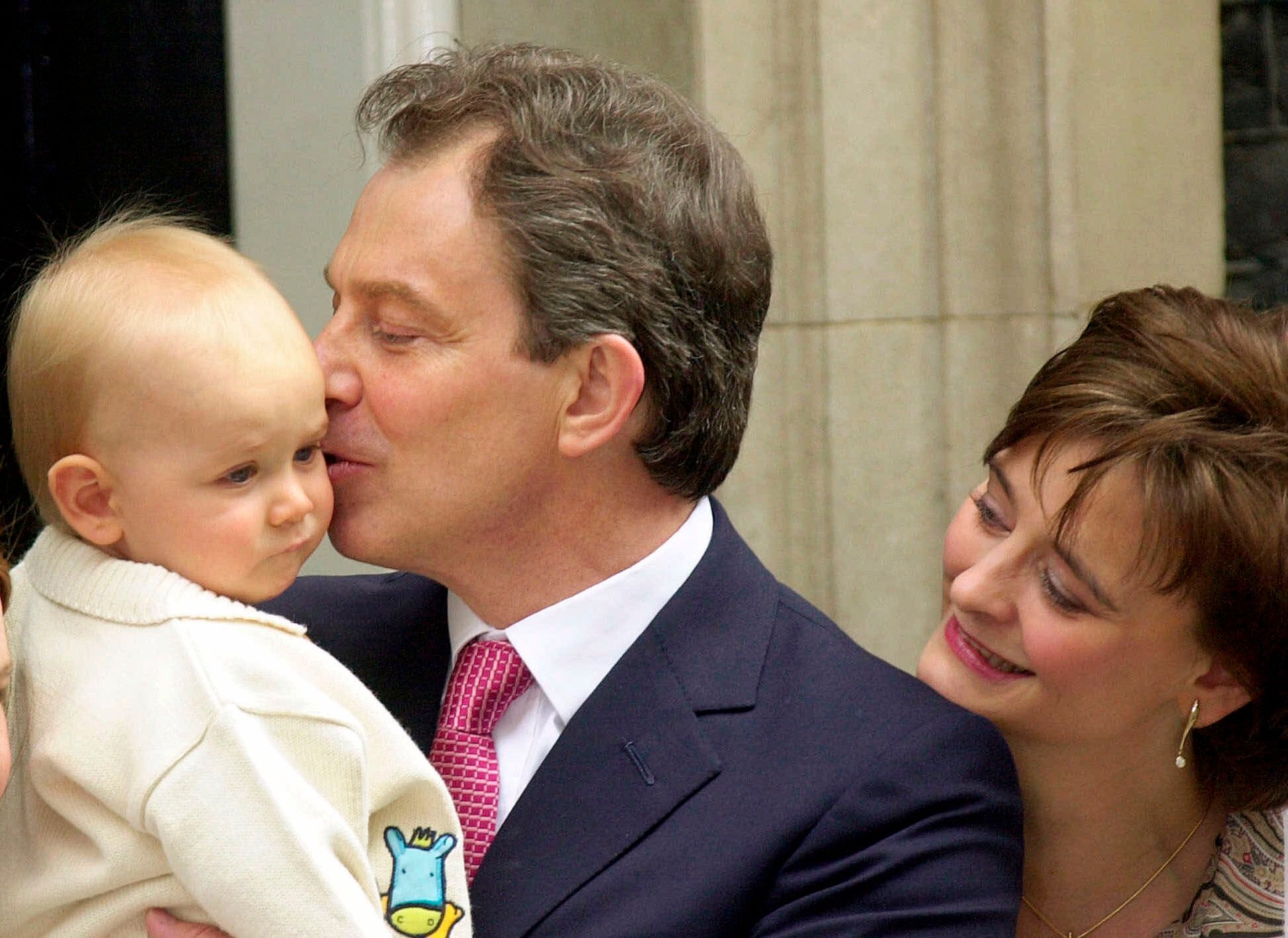 Tony Blair kisses his baby son Leo outside No 10 Downing Street as his wife, Cherie, watches on (8 June 2001)