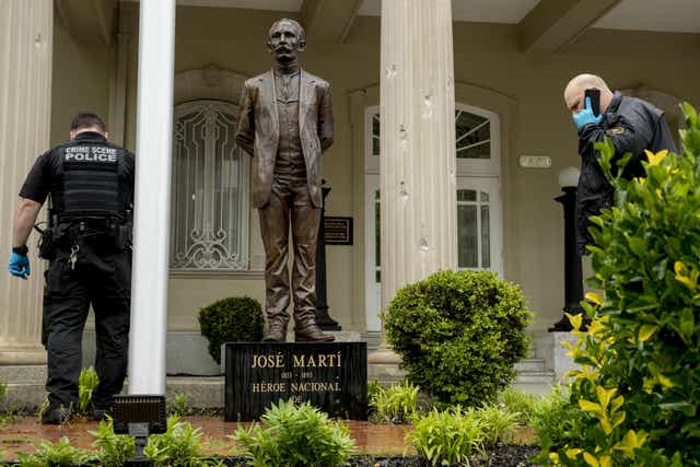 Bullet holes are visible on a column behind a statue of Cuban independence hero José Martí as Secret Service officers investigate after a man with an assault rifle opened fire at the Cuban Embassy in Washington, DC