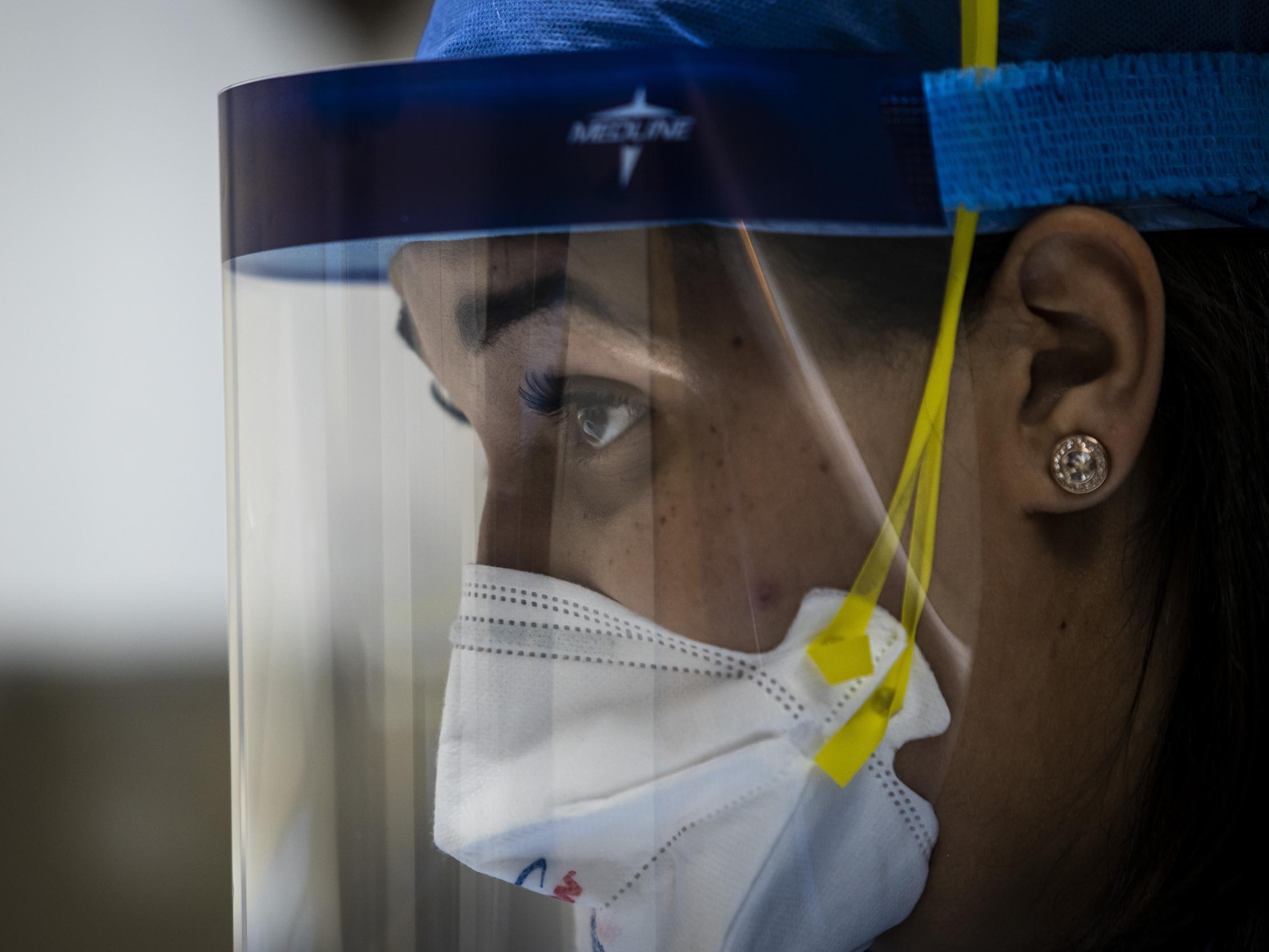 Nurse practitioner Capri Reese talks to a patient while a doctor administers an IV