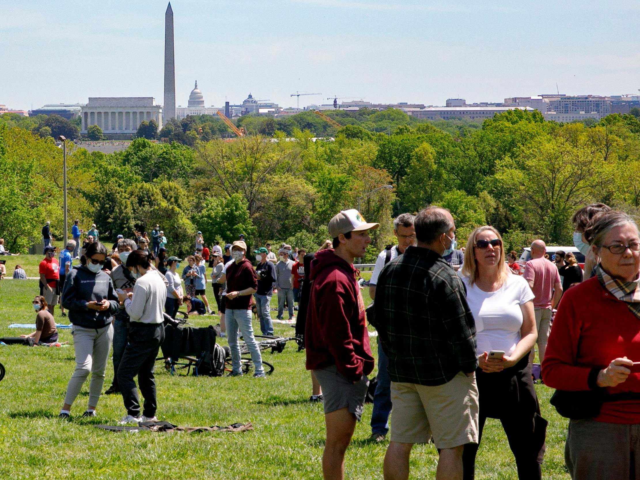 In a mix of masks and not, people wait for the final flyover of the Blue Angels and Thunderbirds in Arlington, Virginia, part of a "salute to frontline COVID-19 responders" on 2 May (AP Photo/Jacquelyn Martin)