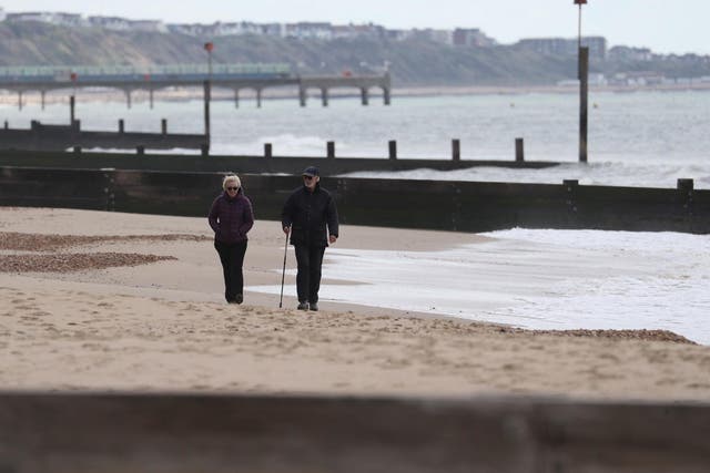 People make their way along a near deserted Bournemouth beach in Dorset as the UK heads towards a seventh week in lockdown on 2 May, 2020.