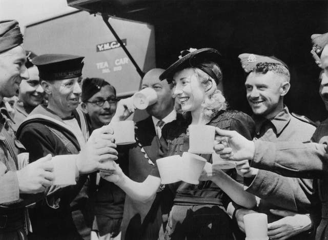 Dame Vera Lynn serves cups of tea to servicemen in 1942