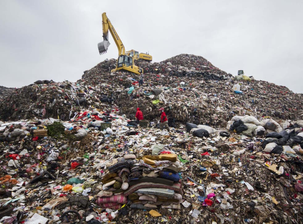 Workers transporting a pile of rubbish at the site in Bekasi, near Jakarta