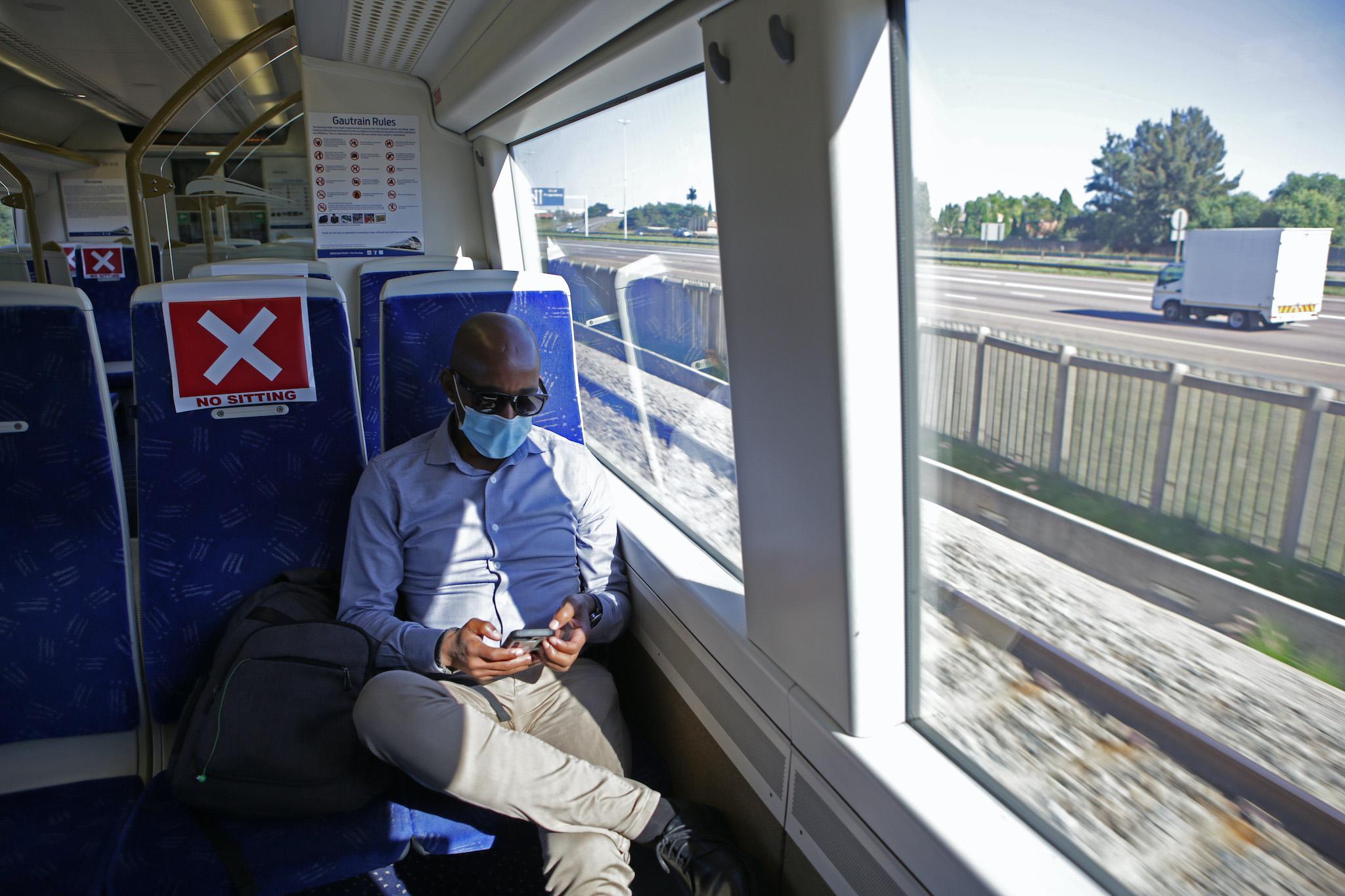 A commuter uses his mobile phone inside the Gautrain after boarding at the Centurion Station in Centurion on May 4, 2020