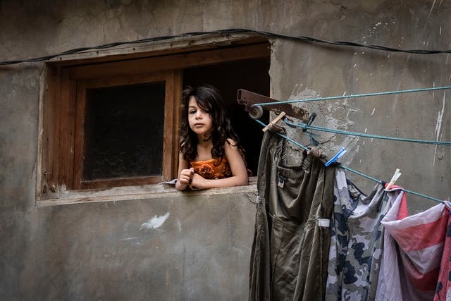 A child looks out of her window in the impoverished neighbourhood of Qobbeh, Tripoli