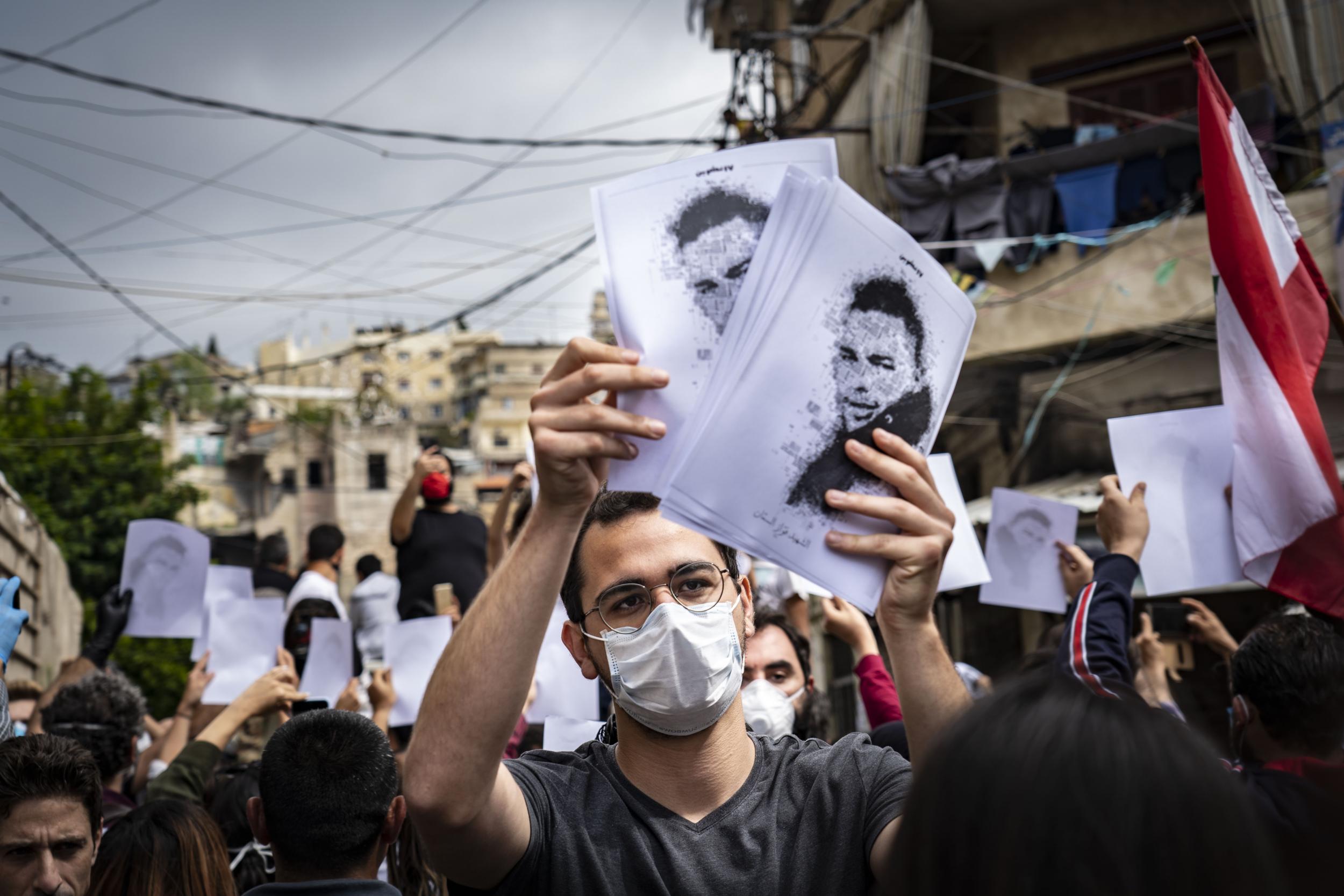 Protesters hold up the image of Fawwaz Fouad al-Seman, a 26-year-old protester killed by security forces last month in Tripoli