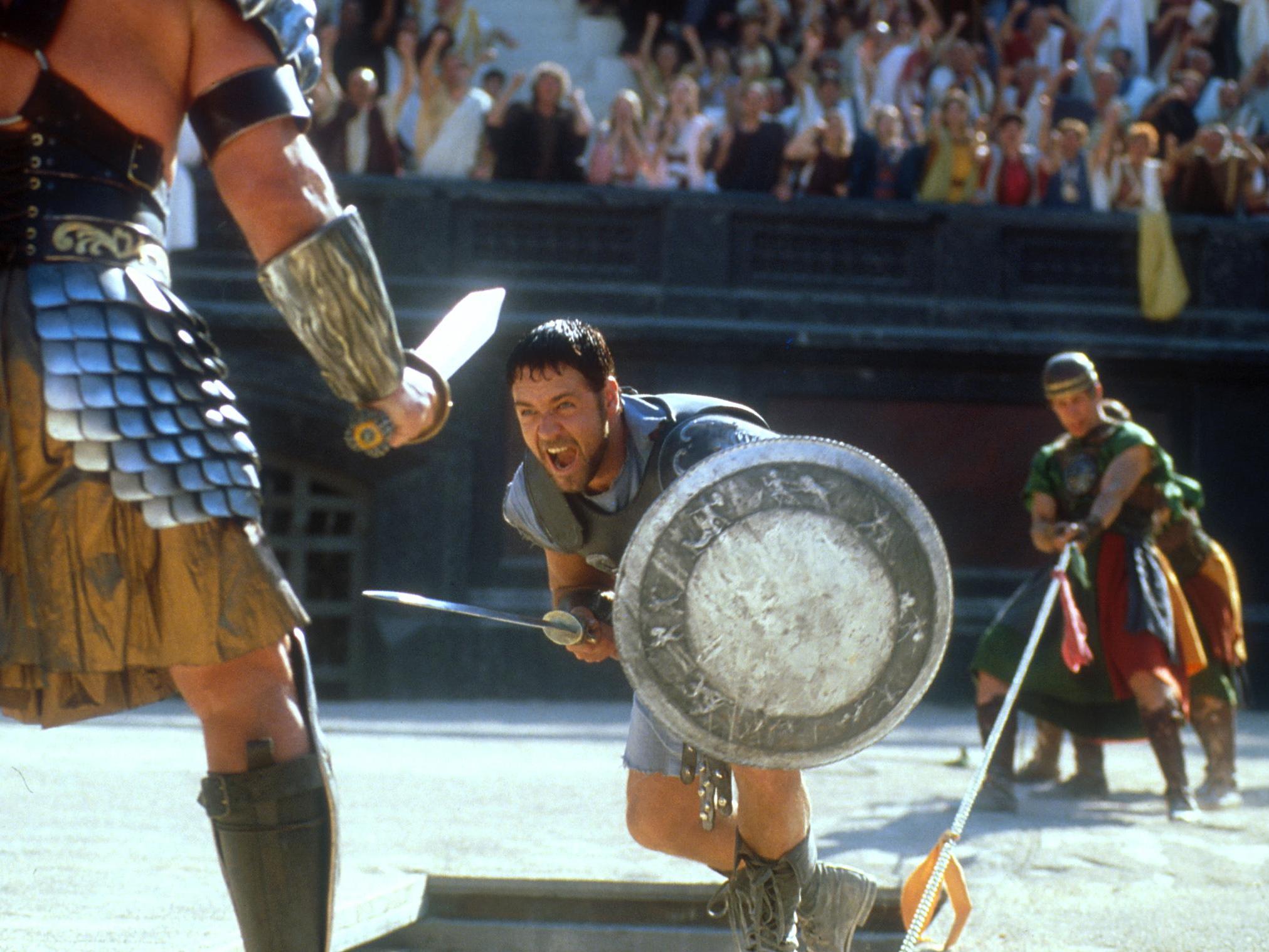 Maximus (Russell Crowe) charges at an opponent in the gladiatorial ring