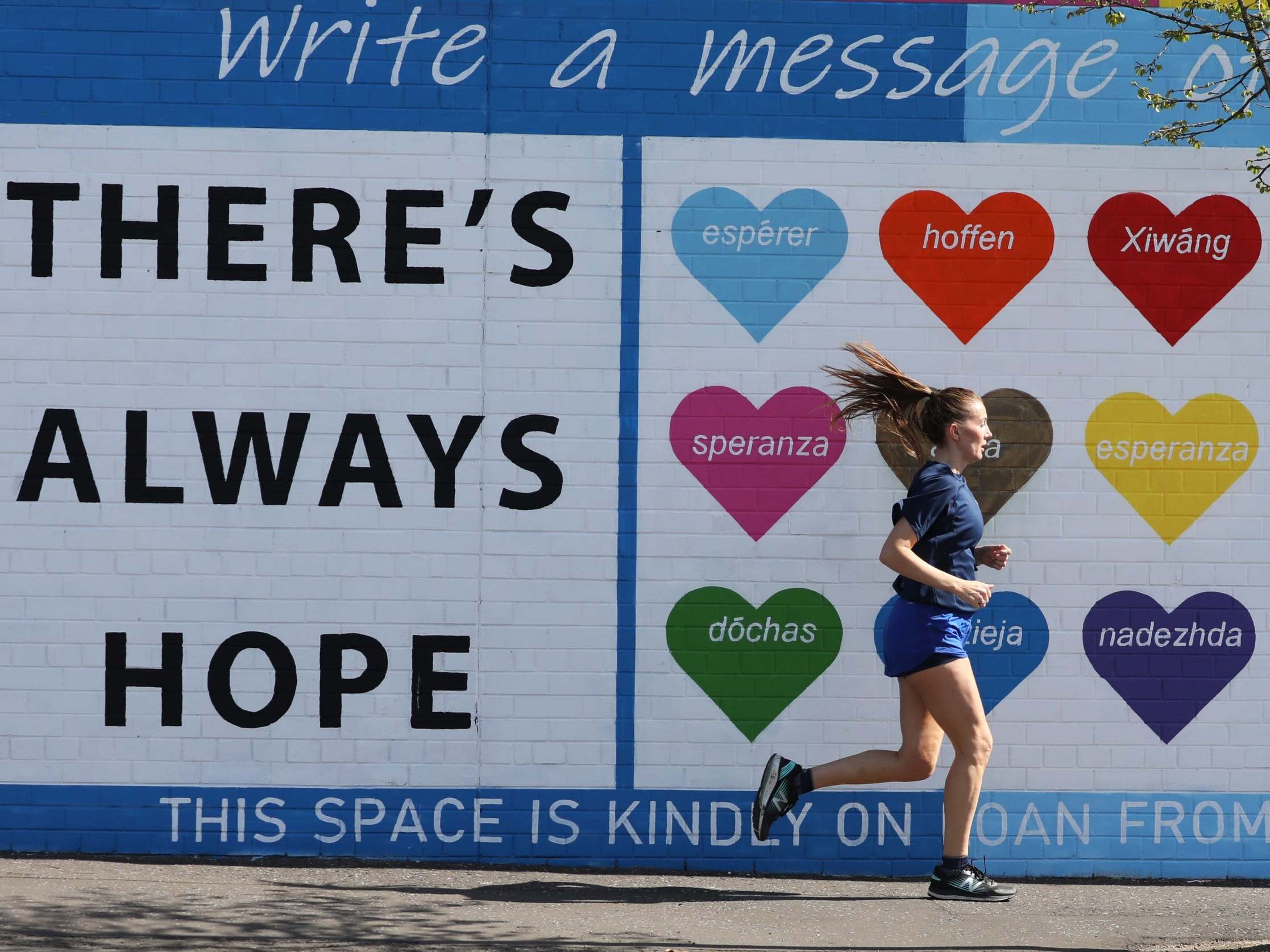 A woman runs past a mental health mural on the Falls road in west Belfast