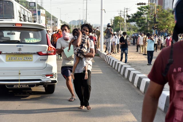 A man runs carrying a child affected by a chemical gas leak in Vishakhapatnam, India, on Thursday