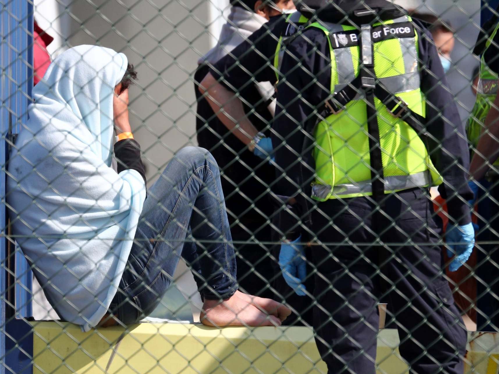 A man thought to be a migrant is processed by Border Force officers after being brought to shore in Dover over the bank holiday weekend