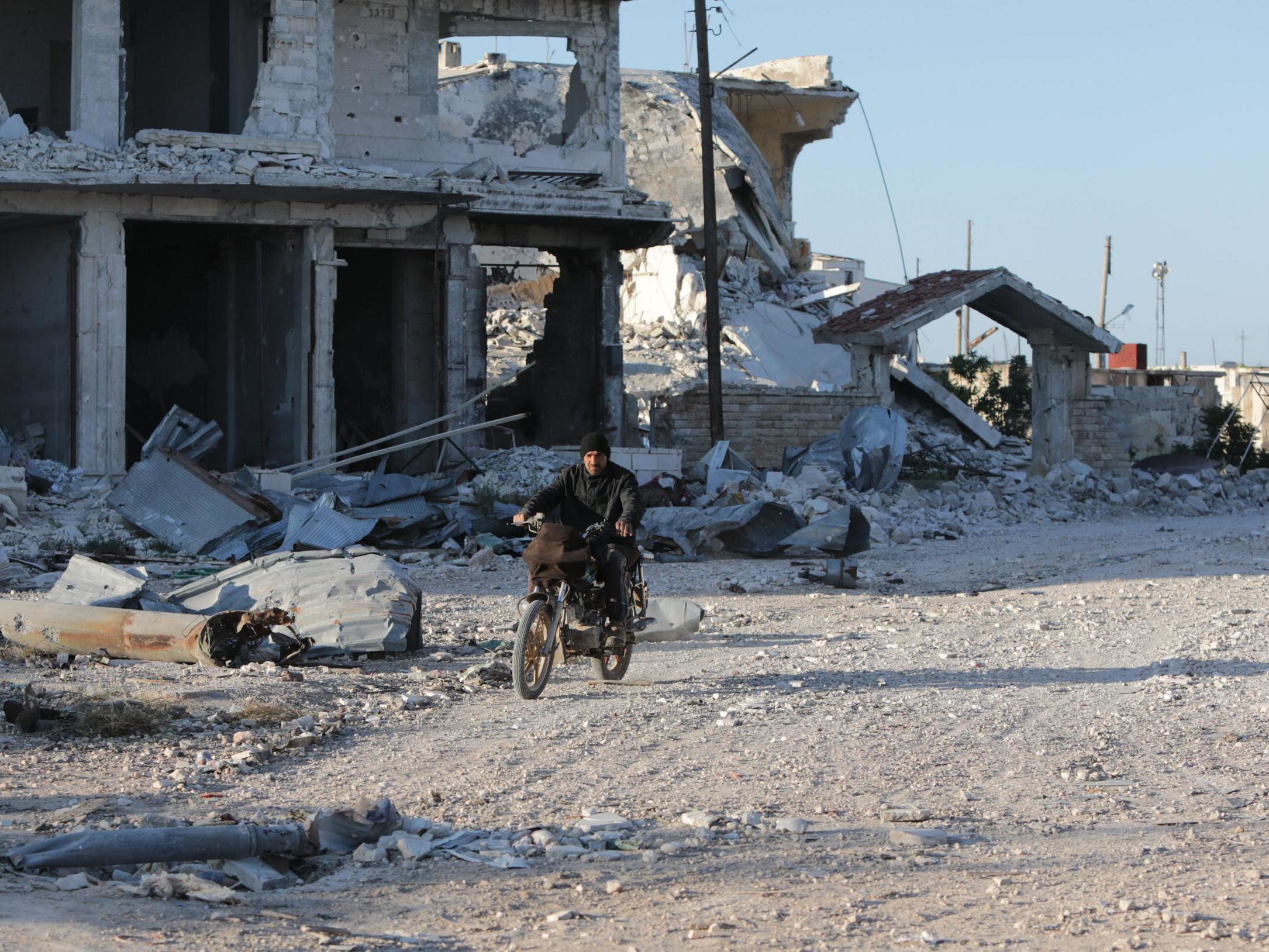 A Syrian man rides his motorcycle in a town ravaged by attacks from pro-government forces in Idlib province