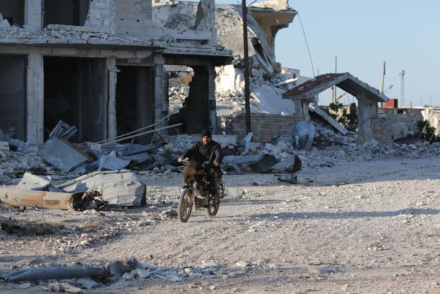 A Syrian man rides his motorcycle in a town ravaged by attacks from pro-government forces in Idlib province